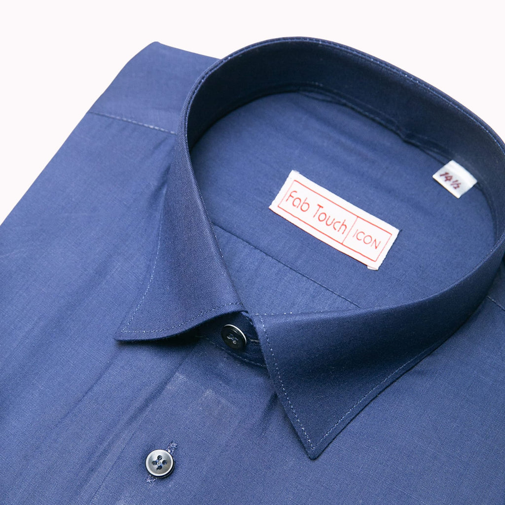 A close-up of a blue long-sleeve dress shirt showing the collar, button, and inner neck label. The label reads 'Fab Touch icon' and there is a small size tag inside the collar.